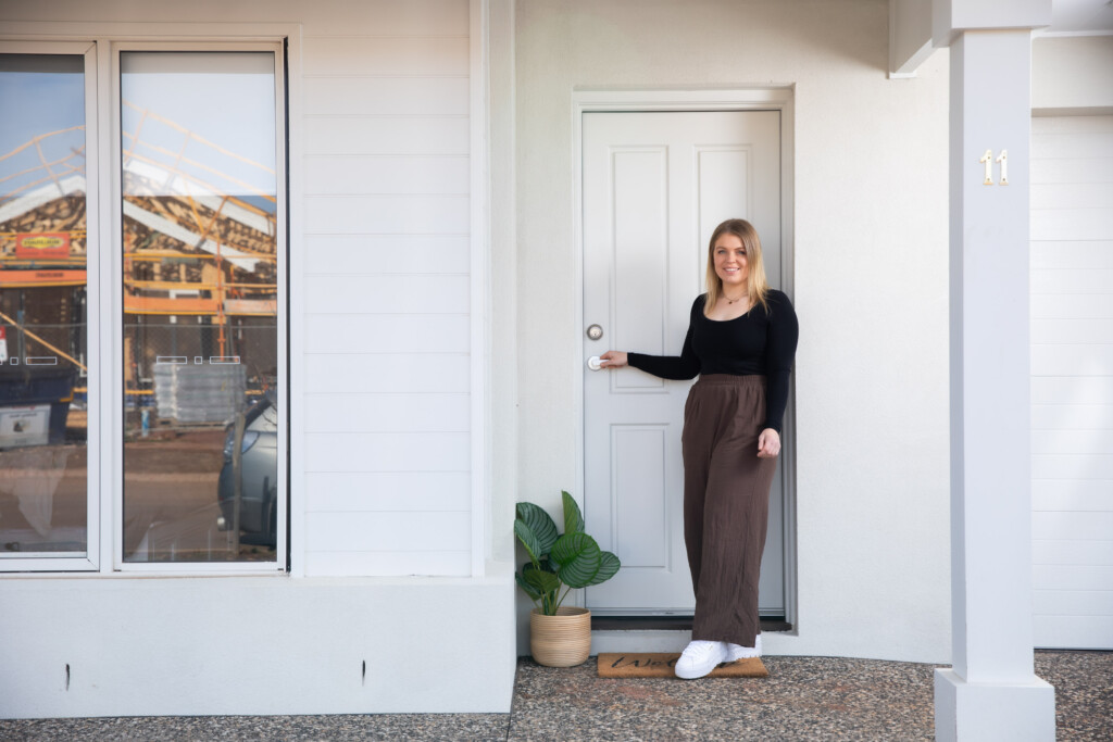 Homeowner standing proudly in front of her new Harvey 23 home built with Homebuyers Centre