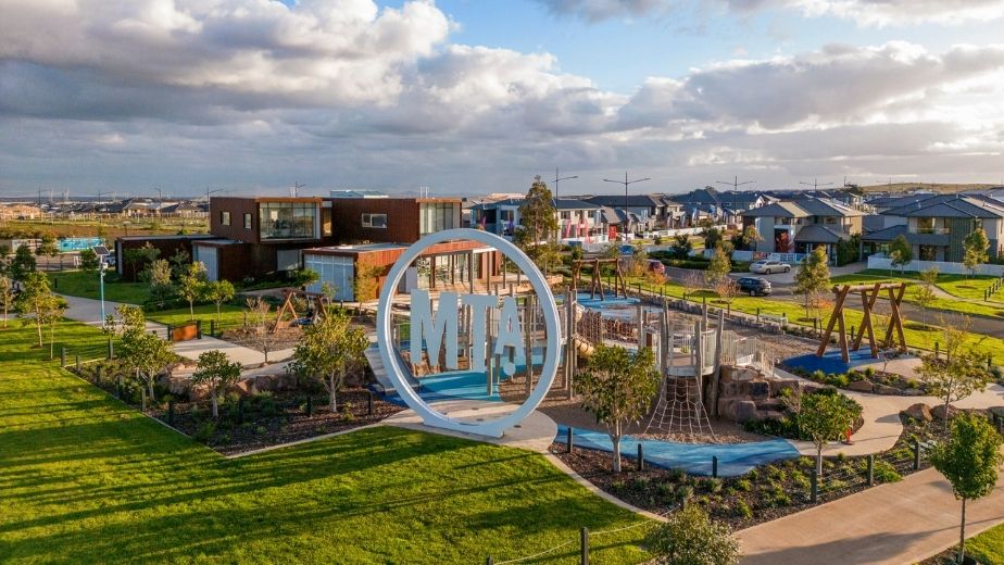 Modern playground and community park at Mt Atkinson Estate in Truganina, featuring landscaped gardens, family spaces, and contemporary homes under a cloudy sky.
